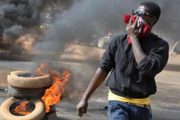 
	Homem se protege da fuma&ccedil;a resultante da queima de pilhas de pneus, no N&iacute;ger
 (Boureima Hama/AFP)