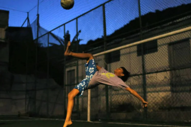
	Um menino chuta a bola para o gol em uma comunidade no Rio Janeiro
 (REUTERS/Pilar Olivares)