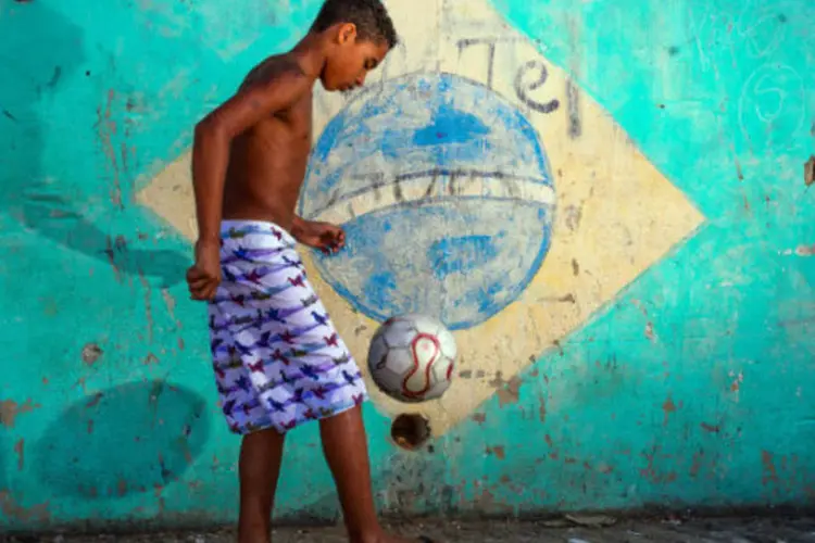 
	Menino faz embaixadinhas em favela no Rio: cerca de metade dos 600.000 visitantes estrangeiros esperados pelo Pa&iacute;s para a Copa visitar&atilde;o o Rio
 (Buda Mendes/Getty Images)