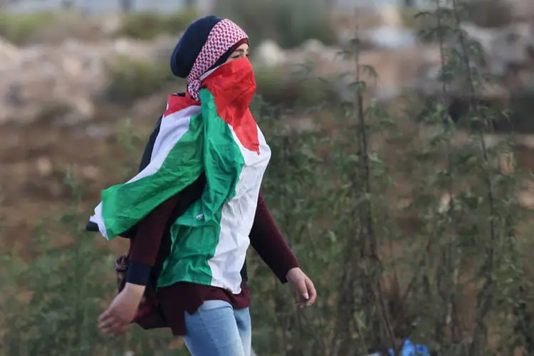 
	Garota palestina veste bandeira em confronto na Cisjord&acirc;nia: ausentes nos primeiros dias de viol&ecirc;ncia, cada vez mais mulheres aderem &agrave; &quot;luta&quot; contra a ocupa&ccedil;&atilde;o israelense nas cidades cisjordanianas
 (Reuters / Mohamad Torokman)