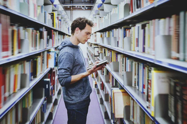 jovem em biblioteca (Thinkstock)