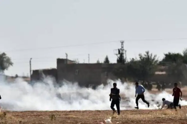 Curdos correm do gás lacrimogêneo lançado pelo Exército turco na fronteira com a Síria (Aris Messinis/AFP)