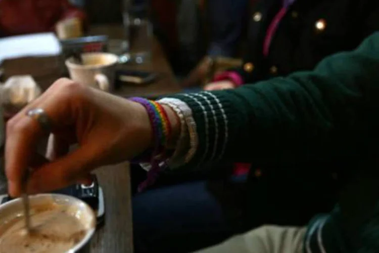 Homem utilizando uma pulseira com as cores do arco-íris, a bandeira do orgulho gay, toma um café em Damasco (AFP)