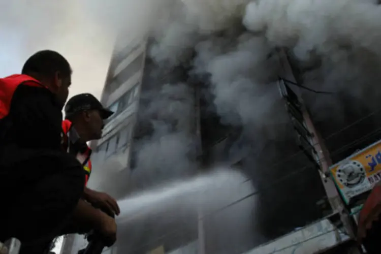 Bombeiros palestinos tentam apagar um incêndio após um ataque aéreo israelense, em Gaza (REUTERS/Suhaib Salem)