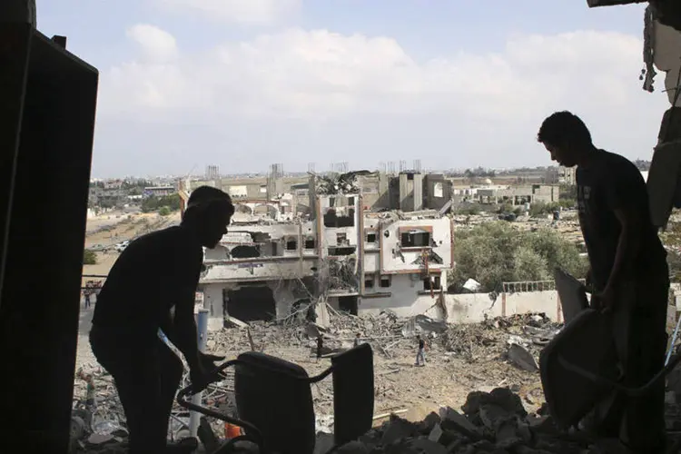 
	Palestinos recuperam seus pertences de casa fortemente danificada em ataque israelense em Rafah
 (REUTERS/Ibraheem Abu Mustafa)