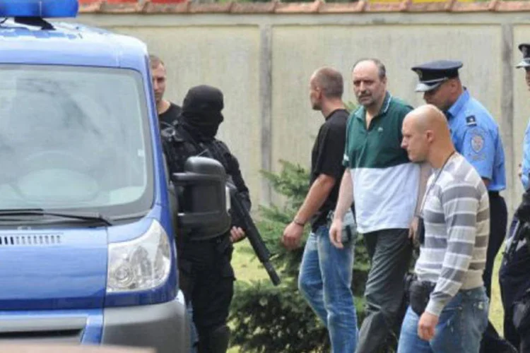 Hadzic (ao centro) é escoltado pela polícia até o embarque em uma viatura, que o levou ao aeroporto de Belgrado
 (AFP)