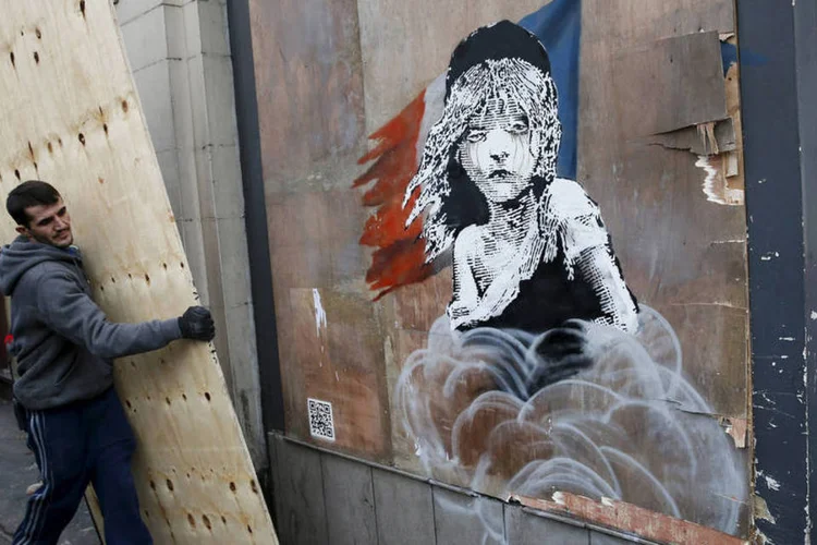 
	Homem coloca tapume para cobrir grafite de Banksy: apesar de suas obras serem vistas desde o come&ccedil;o dos anos 2000, ningu&eacute;m sabe a identidade do artista
 (Stefan Wermuth / Reuters)