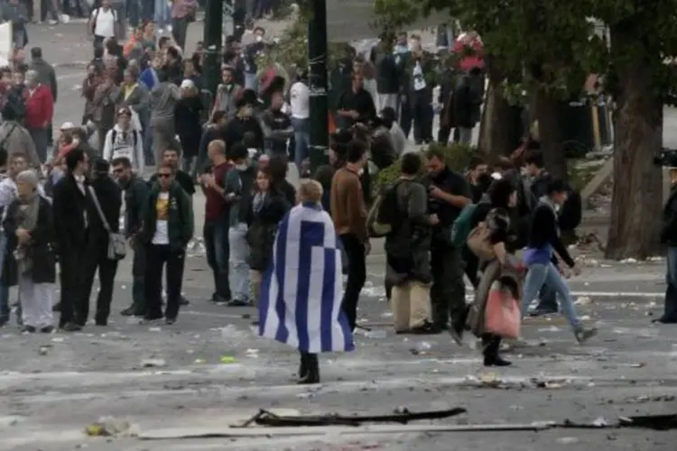 Mulher caminha com a bandeira da Grécia no meio da mobilização (Milos Bicanski/Getty Images)