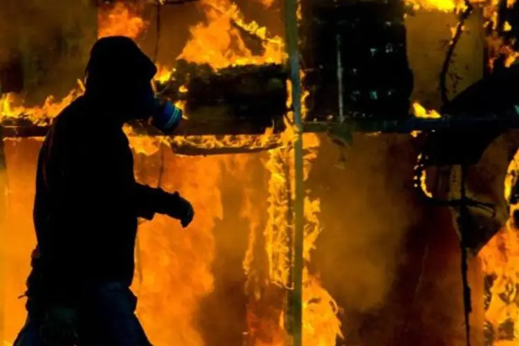 Homem caminha na frente de local em chamas, na Grécia (Milos Bicanski/Getty Images)