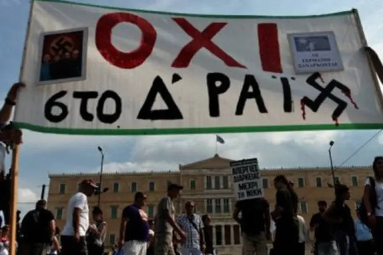 Manifestantes seguram banner com frase "Não ao quarto reich" em protesto contra Angela Merkel em frente ao Parlamento de Atenas
 (Aris Messinis/AFP)