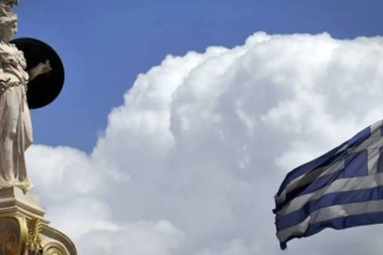 Estátua e bandeira da Grécia: Segundo dados oficiais, em 2011 foram arrecadados 1,8 bilhão de euros com as privatizações (Louisa Gouliamaki/AFP)