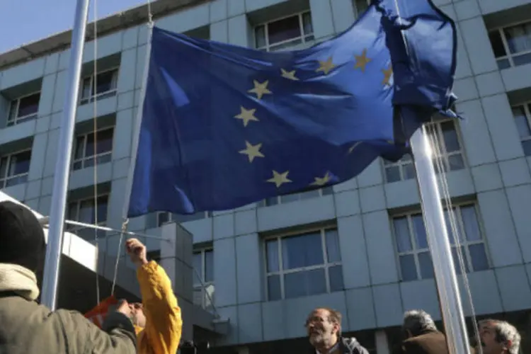 Trabalhadores de Atenas puxam para baixo bandeira da União Europeia durante uma manifestação contra as demissões exigidas pelos credores internacionais da Grécia (REUTERS / John Kolesidis)