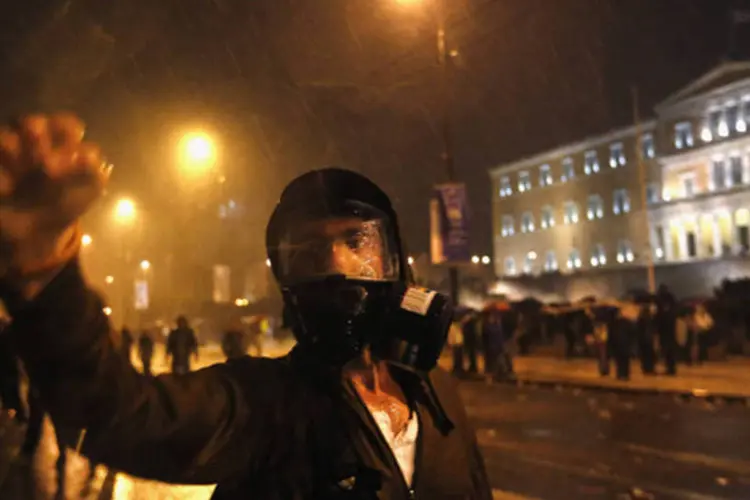 
	Um manifestante vestindo uma m&aacute;scara de g&aacute;s levanta o punho durante uma manifesta&ccedil;&atilde;o na Pra&ccedil;a Syntagma, no centro de Atenas: &nbsp;Gr&eacute;cia caminha para o sexto ano de recess&atilde;o em 2013
 (Yannis Behrakis/Reuters)