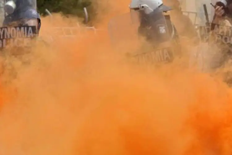 Policiais aparecem entre fumaça de gás lacrimogêneo  (Aris Messinis/AFP)