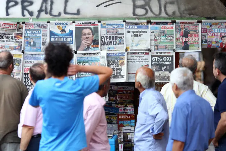 Gregos observam as manchetes dos jornais na manhã desta segunda-feira em Atenas, na Grécia (Chris Ratcliffe/Bloomberg)