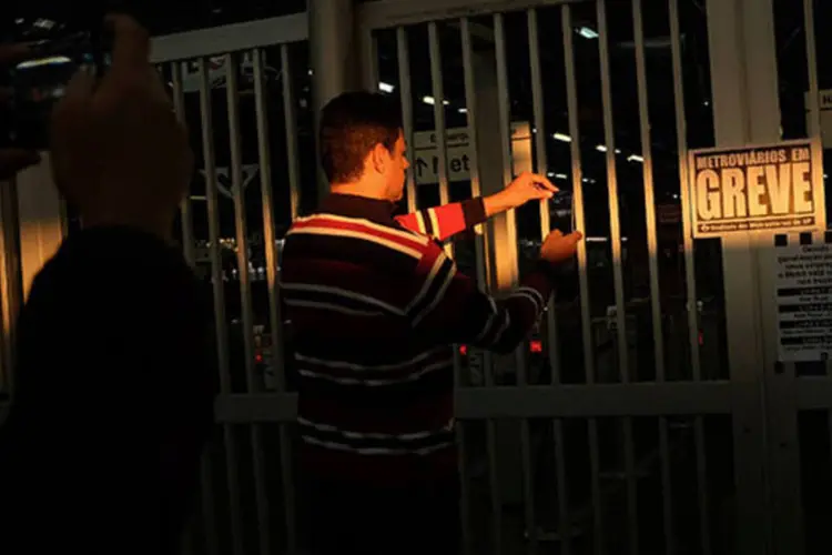 Homem tira foto de cartaz de greve em frente ao portão fechado na estação Barra Funda (REUTERS/Nacho Doce)