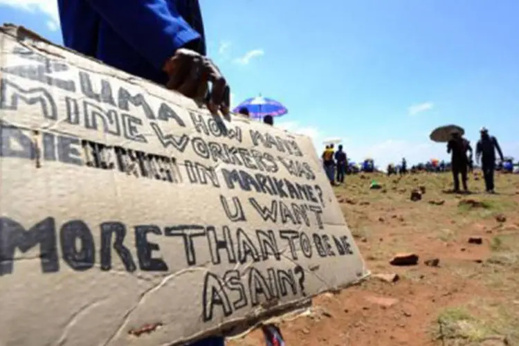 
	Grevista segura um cartaz em protesto em uma mina em Carletonville: o aumento oscila entre 11% e 20,8%
 (Alexander Joe/AFP)
