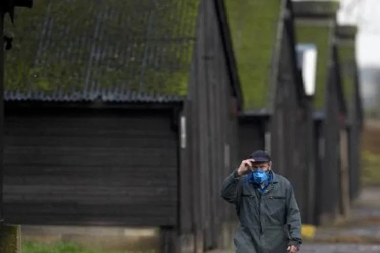 Homem vestindo uma máscara caminha em uma fazenda onde um caso de gripe aviária foi registrado, na cidade britânica de Nafferton (Oli Scarff/AFP)