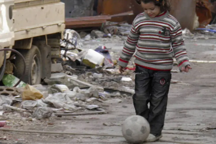 Menina brinca com uma bola em uma rua na área sitiada de Homs, na Síria (Thaer Al Khalidiya/Reuters)