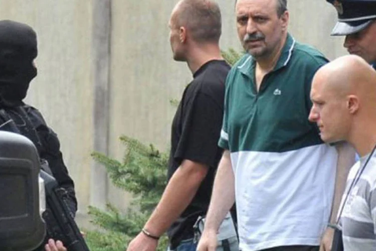 Hadzic (ao centro) deixa a cadeia escoltado por policiais: ele é acusado de crimes de guerra e contra a humanidade (AFP)