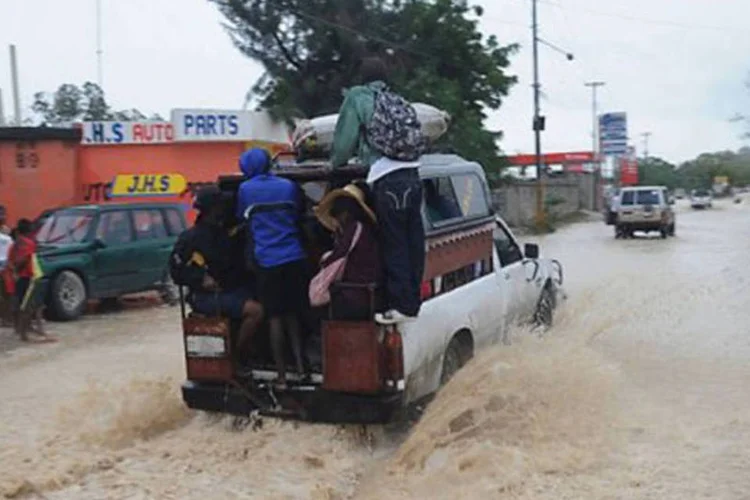 
	Haitianos dirigem por ruas alagadas em Porto Pr&iacute;ncipe, Haiti, em 25 de agosto de 2012: cerca de 15 mil pessoas foram retiradas de suas casas
 (Thony Belizaire/AFP)