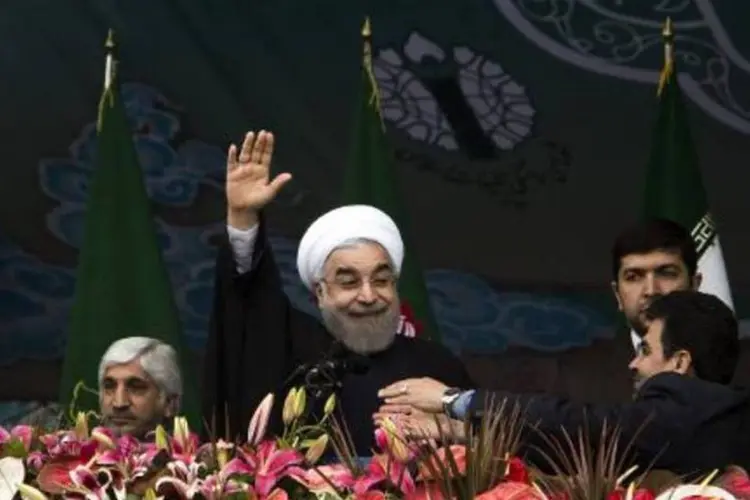 Rouhani acena para partidários na Praça Azadi, em Teerã: "na região do Oriente Médio, instaurar a paz e a estabilidade e erradicar o terrorismo passa pela República Islâmica do Irã" (Behrouz Mehri/AFP)