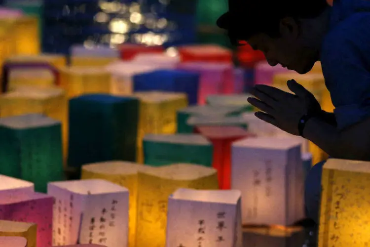 Homem rezando após colocar uma lanterna de papel no rio Motoyasu (REUTERS/Toru Hanai)