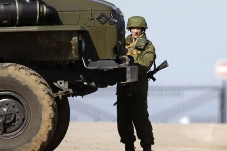 Homen armado, tido como soldado russo, monta guarda perto de uma pista de pouso na aldeia de Lyubimovka, na Crimeia, Ucrânia (Vasily Fedosenko/Reuters)