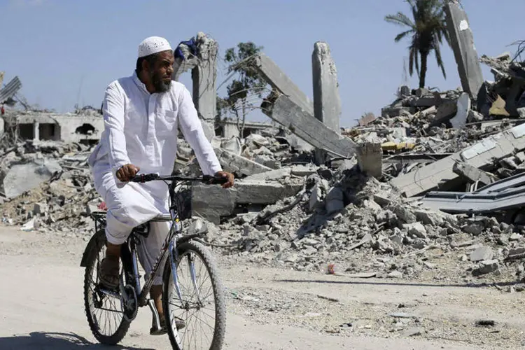 
	Palestino passa de bicicleta em frente a casas destru&iacute;das em Khuzaa,na Faixa de Gaza
 (REUTERS/Ibraheem Abu Mustafa)
