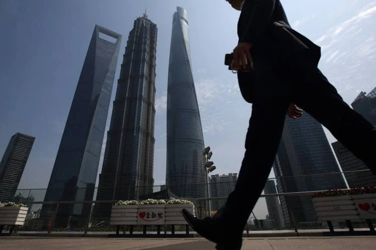 Homem caminha diante de torres em Xangai, na China: país esta no centro das preocupações globais (Tomohiro Ohsumi/Bloomberg)