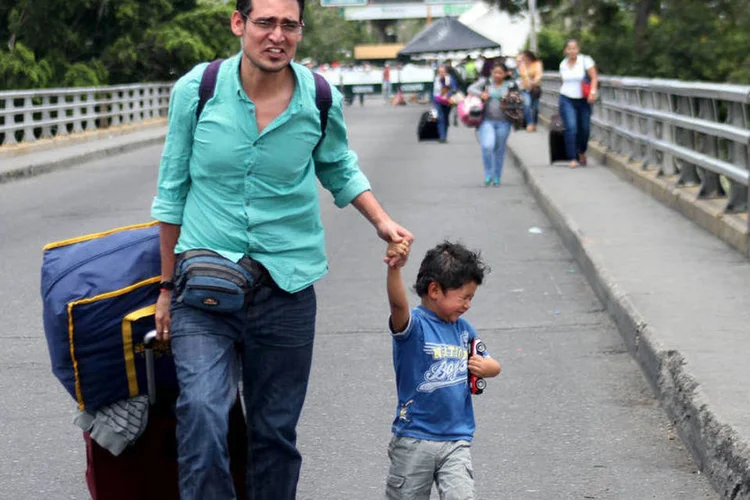 
	Homem e crian&ccedil;a cruzam fronteira da Venezuela com a Col&ocirc;mbia: na capital do departamento, C&uacute;cuta, est&aacute; montada uma base de assist&ecirc;ncia humanit&aacute;ria para atender os desabrigados pela crise
 (Reuters / Manuel Hernandez)