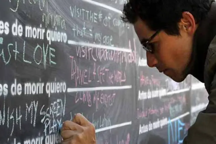 Jovem escrevendo em lousa em lista (Foto/Getty Images)