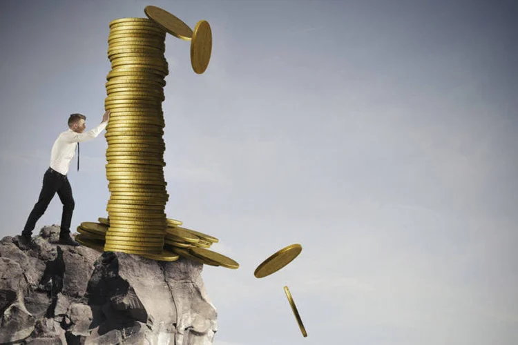 
	Homem e coluna de moedas perto de precip&iacute;cio: Viver um dia de cada vez pode prejudicar as finan&ccedil;as pessoais
 (alphaspirit/Thinkstock)