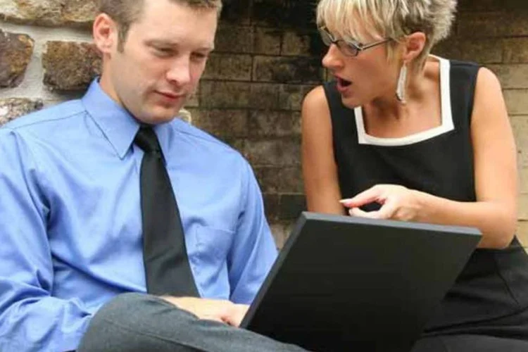 Executivo e executiva usando notebook no trabalho (Dreamstime/Reprodução)