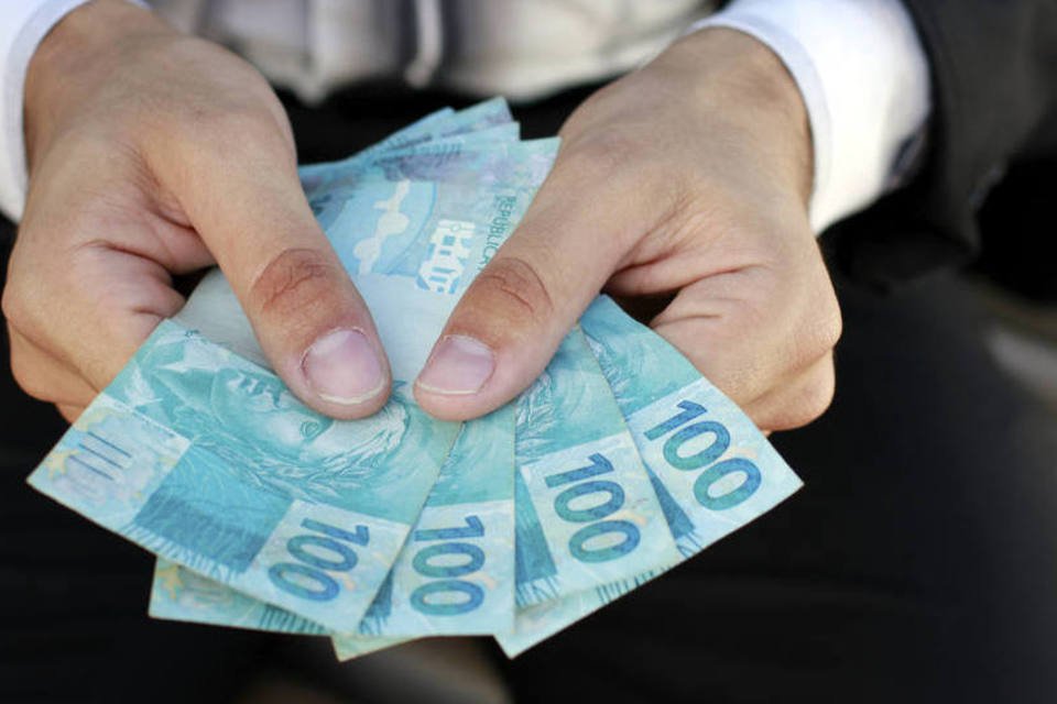 Homem segura notas de 100 reais (ThinkStock/Uelder Ferreira)
