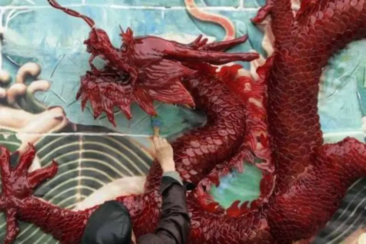 Um trabalhador pinta o cenário de um muro, com nove dragões instalados feitos de açúcar, durante a preparação do Ano Novo Lunar em um parque em Chengdu, na província de Sichuan (Reuters)