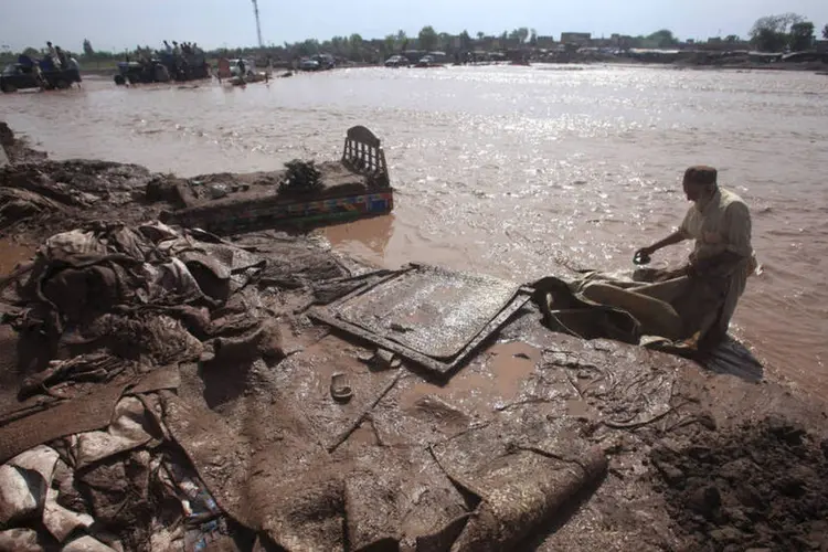 
	Homem tenta salvar pertences em enchente no Paquist&atilde;o, em abril
 (Fayaz Aziz/ Reuters)