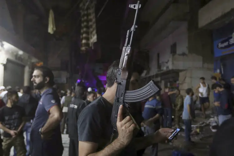 
	Homem usa celular enquanto tem arma em punho na regi&atilde;o de atentado suicida em Beirute: trata-se do primeiro atentado nesta regi&atilde;o do sul de Beirute desde junho de 2014
 (Hasan Shaabanâ/ Reuters)