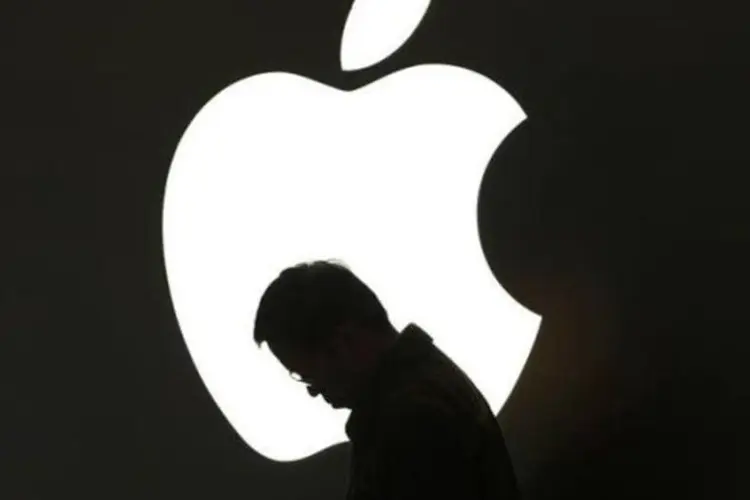 Homem olha seu iPad em frente ao logo da Apple em loja no centro de Xangai (Aly Song/Reuters)