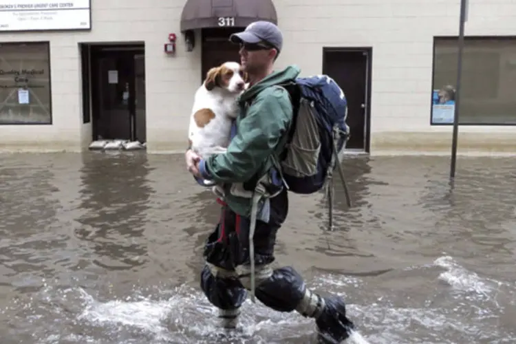 Homem carrega cachorro em meio a inundação causada por furacão Sandy: muitas pessoas optaram por se locomover andando hoje (REUTERS)