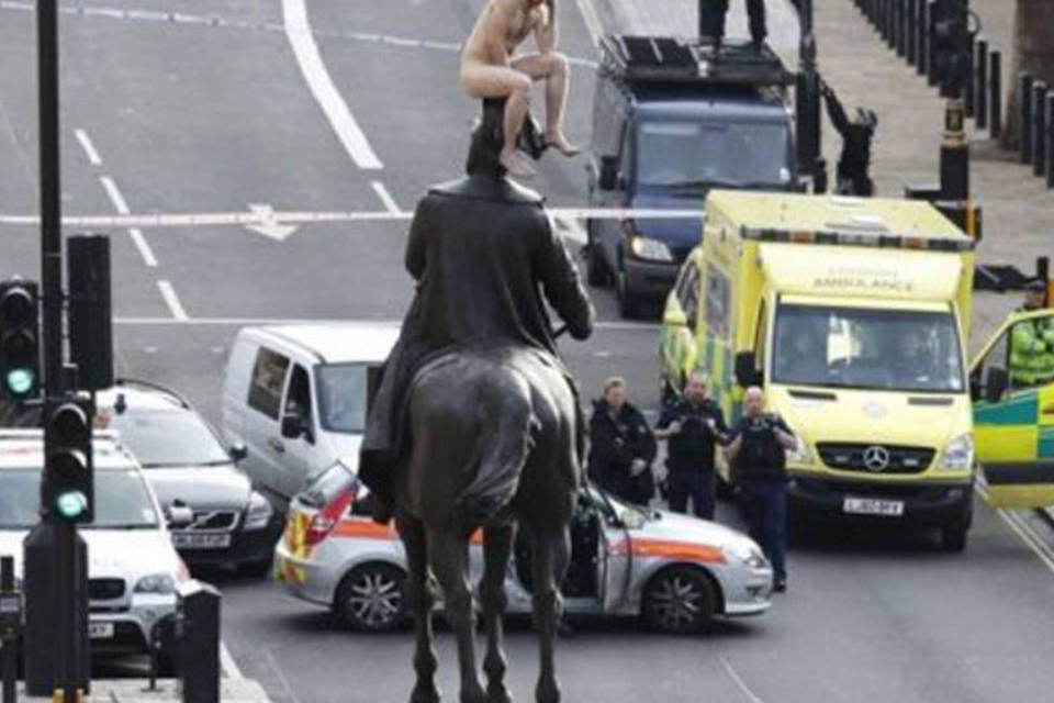 Um homem nu senta no topo de uma estátua no centro de Londres: do meio-dia às três da tarde, a polícia isolou a área para convencer o homem a descer (©AFP / Justin Tallis)