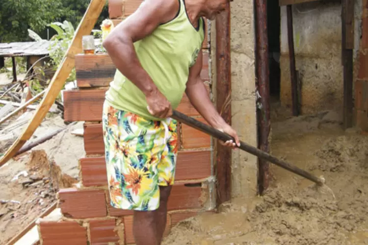 
	Homem tira lama de dentro de sua casa em Xer&eacute;m, distrito de Duque de Caxias (RJ)
 (Fotorepórter Vladimir Platonov/ABr)