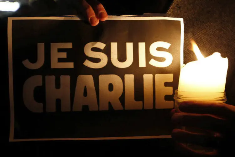 
	Pessoa segura vela ao lado de cartaz onde se l&ecirc; &quot;Eu sou Charlie&quot;, em apoio &agrave; revista Charlie Hebdo
 (Vincent Kessler/Reuters)