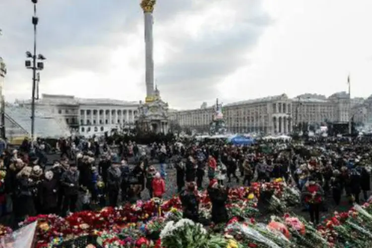 Pessoas prestam homenagens aos manifestantes anti-governo mortos em Kiev: presidente interino estimou que referendo será "farsa" decidida nos "gabinetes do Kremlin" (AFP)