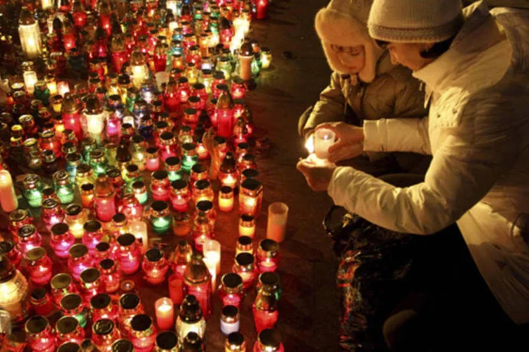 Mulher acende uma vela em homenagem aos mortos nos protestos anti-governo da praça da Independência de Kiev, na Ucrânia (Marian Striltsiv/Reuters)