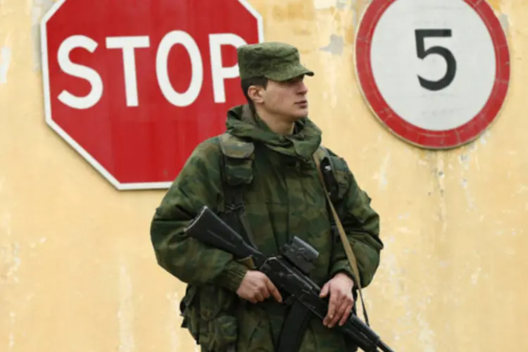 Homem armado, que se acredita estar a serviço da Rússia, monta guarda no em frente a uma área militar ucraniana na cidade de Sevastopol, na região da Crimeia (David Mdzinarishvili/Reuters)