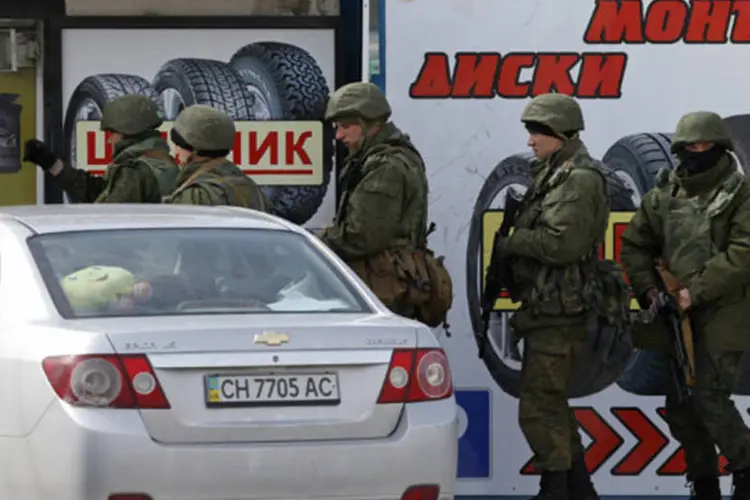 Homens armados, tidos como militares russos, na frente de uma loja fora da base naval em Sebastopol, na Crimeia (Vasily Fedosenko/Reuters)