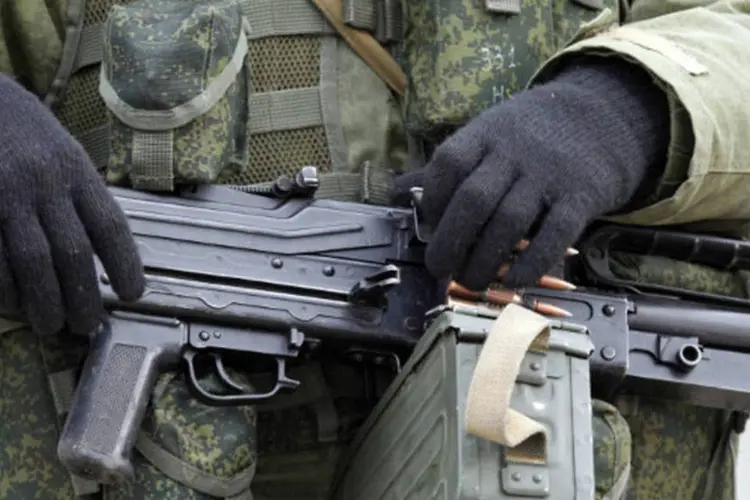 Homem armado, que se acredita estar a serviço da Rússia, monta guarda no em frente a uma área militar ucraniana na vila de Perevalnoye (Vasily Fedosenko)