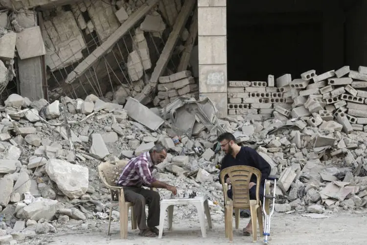 
	Homens jogam xadrez em frente a pr&eacute;dio destru&iacute;do em cidade s&iacute;ria controlada por rebeldes: o regime atualmente n&atilde;o controla mais de 30% do territ&oacute;rio
 (Reuters / Khalil Ashawi)