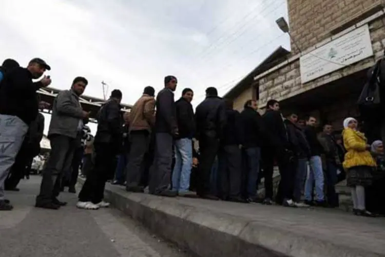 Homens sírios e palestinos fazem fila para carimbar documentos na entidade de imigração localizada na fronteira entre Líbano e Síria (REUTERS/Jamal Saidi)
